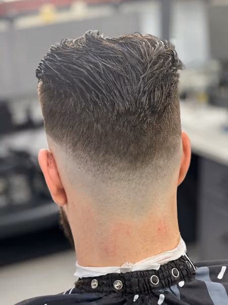 High Drop Skin Fade & Textured Slick Back - Flowing textured sweep on top with an aggressive high drop fade that tapers into a clean V-neckline.